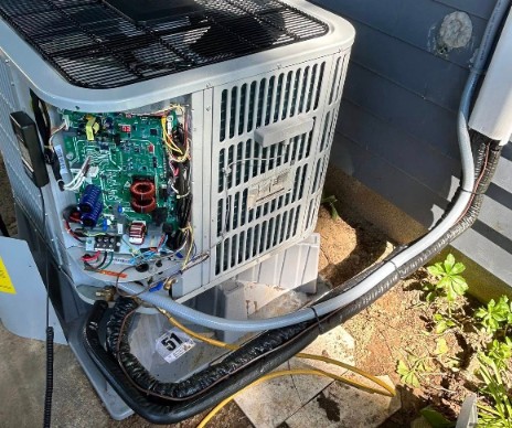 Technician repairing the circuit board of a residential outdoor AC unit in Delano, CA